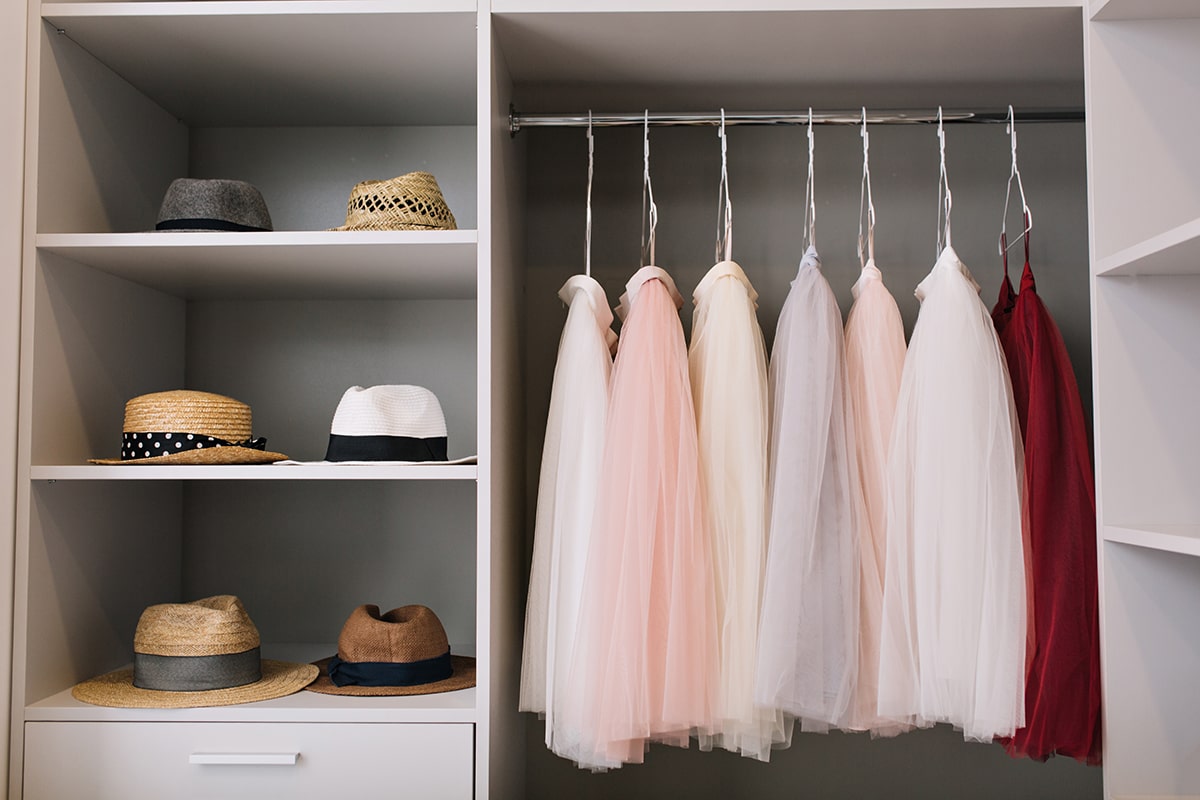 modern-bright-dressing-room-with-shelves-fashionable-hats-beautiful-pink-red-dresses-hanging-wardrobe-min